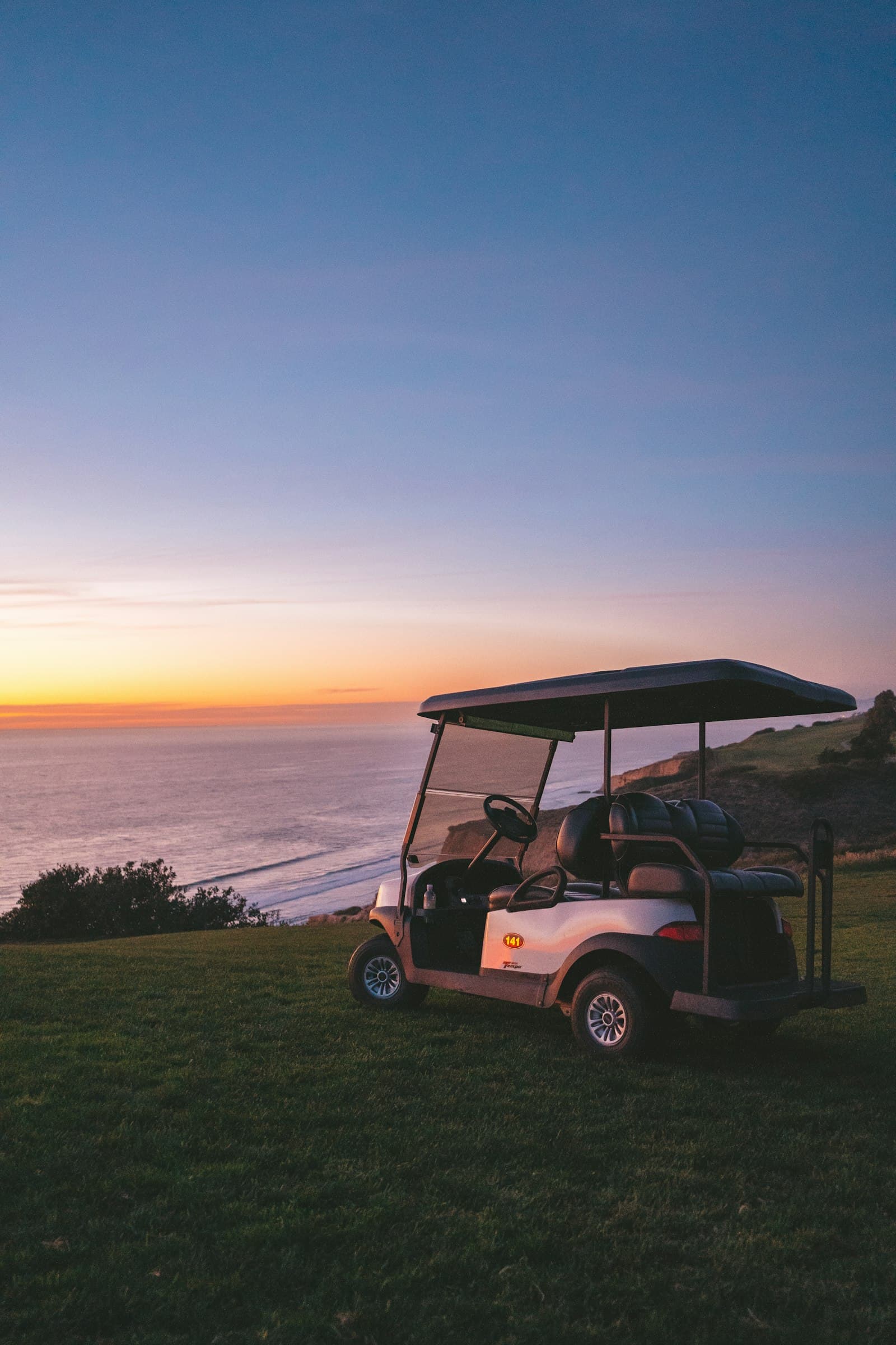 Golf cart parked on a coastal hill at sunset, the kind of ride used to get around San Pedro, Belize